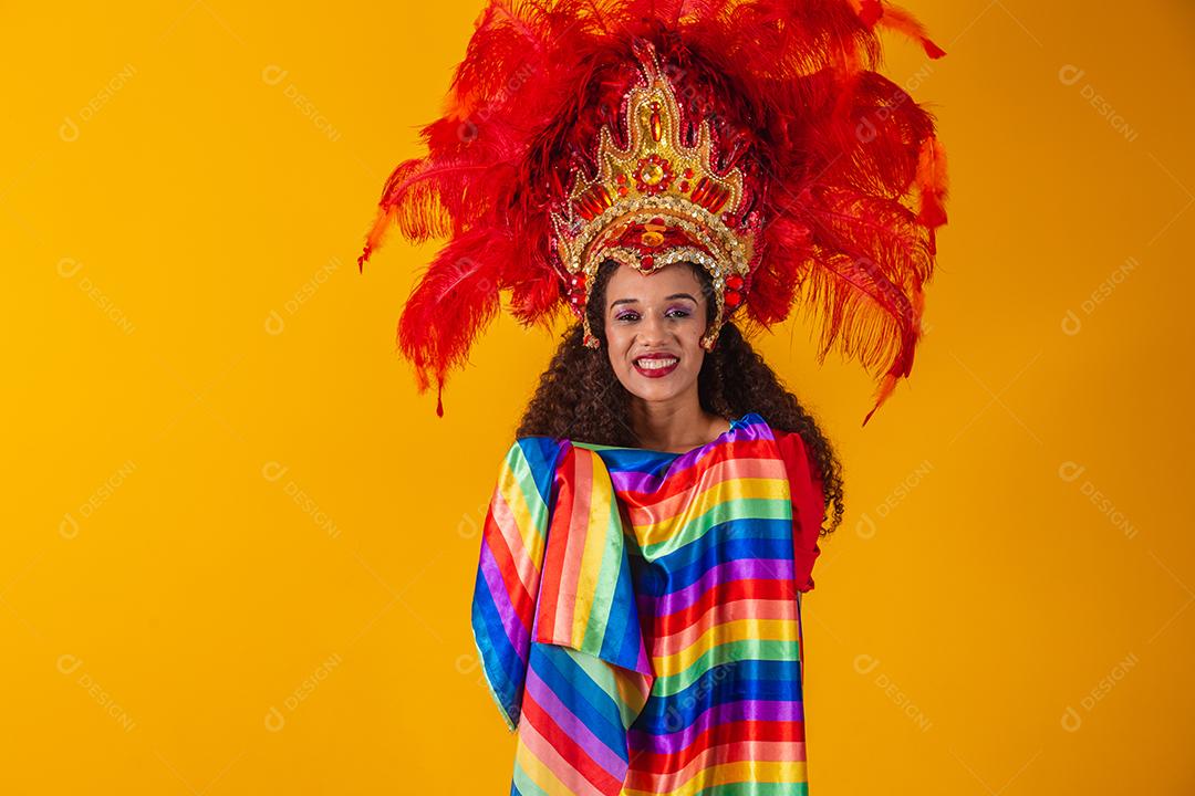Linda mulher afro com roupa de carnaval de bandeira lgbt em fundo amarelo.