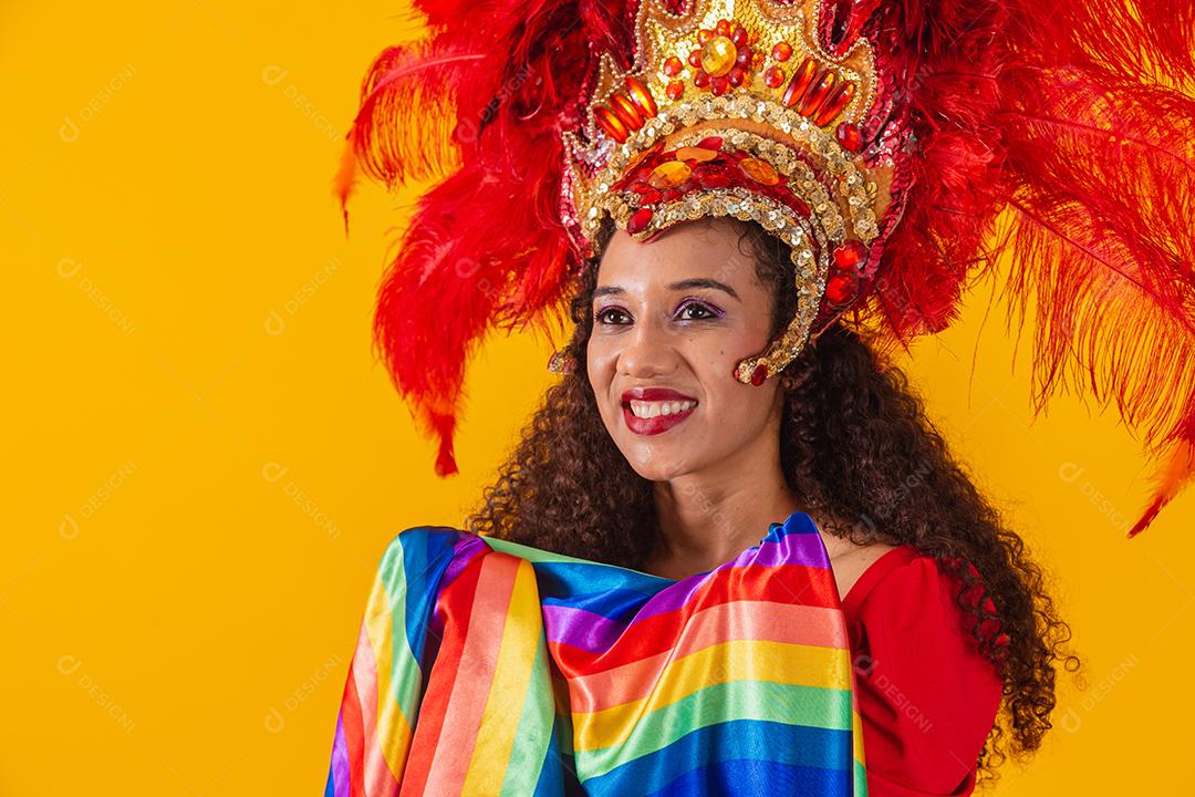 Linda mulher afro com roupa de carnaval de bandeira lgbt em fundo amarelo.