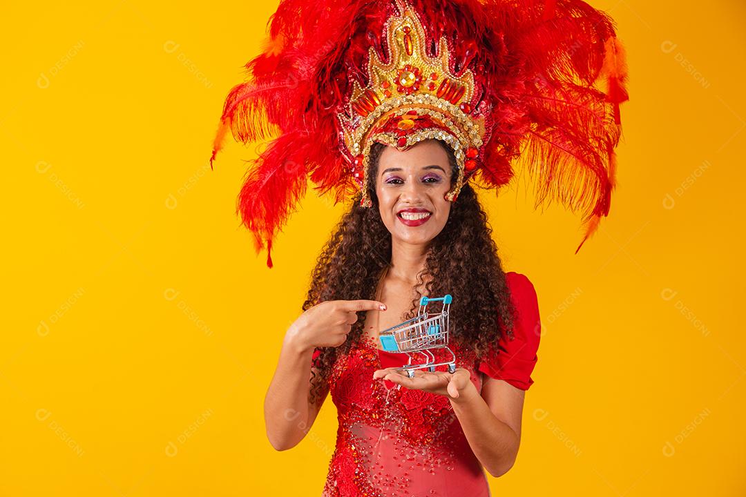 Linda mulher afro com roupa de carnaval e samba com mini carrinho de supermercado na mão