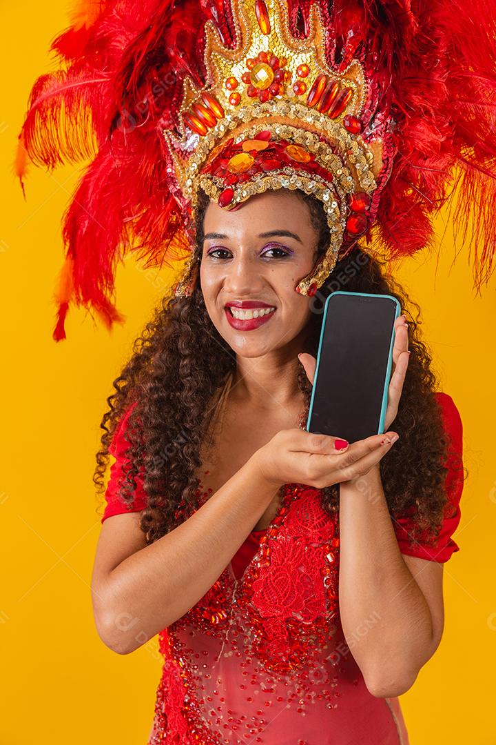 Mulher jovem e bonita em traje especial de penas de carnaval segurando um smartphone