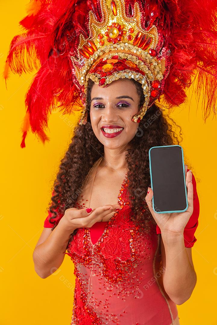 Mulher jovem e bonita em traje especial de penas de carnaval segurando um smartphone