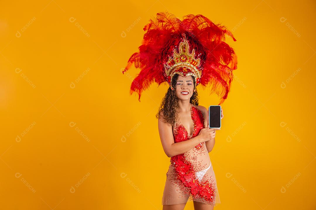 Mulher jovem e bonita em traje especial de penas de carnaval segurando um smartphone