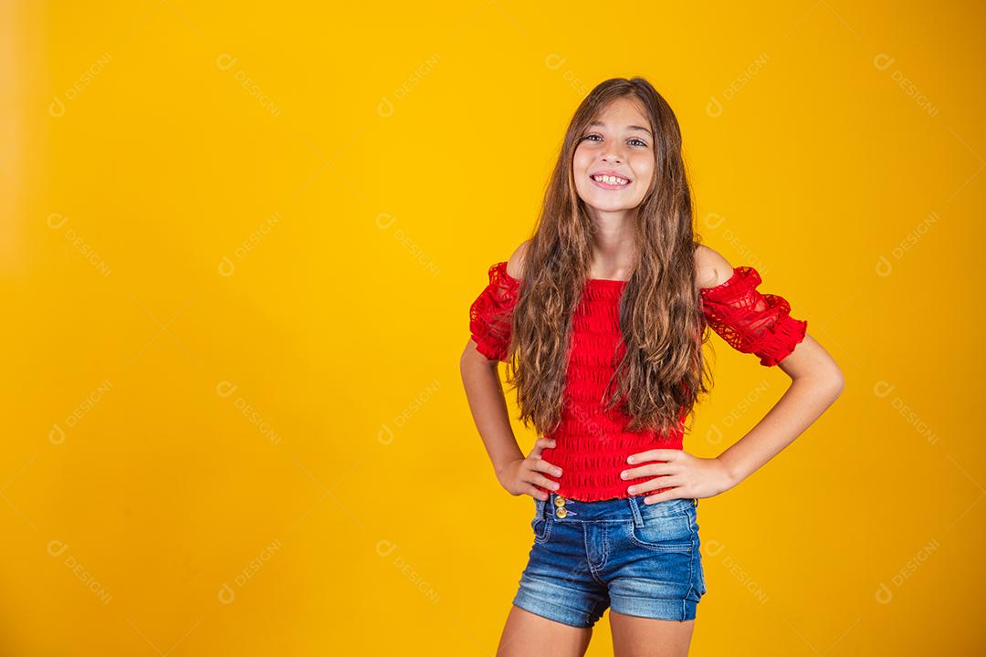 Criança menina feliz em fundo amarelo sorrindo olhando para a câmera.