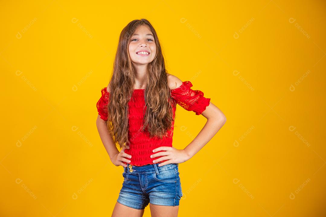 Criança menina feliz em fundo amarelo sorrindo olhando para a câmera.