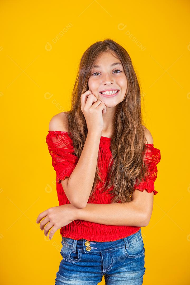 Criança menina feliz em fundo amarelo sorrindo olhando para a câmera.