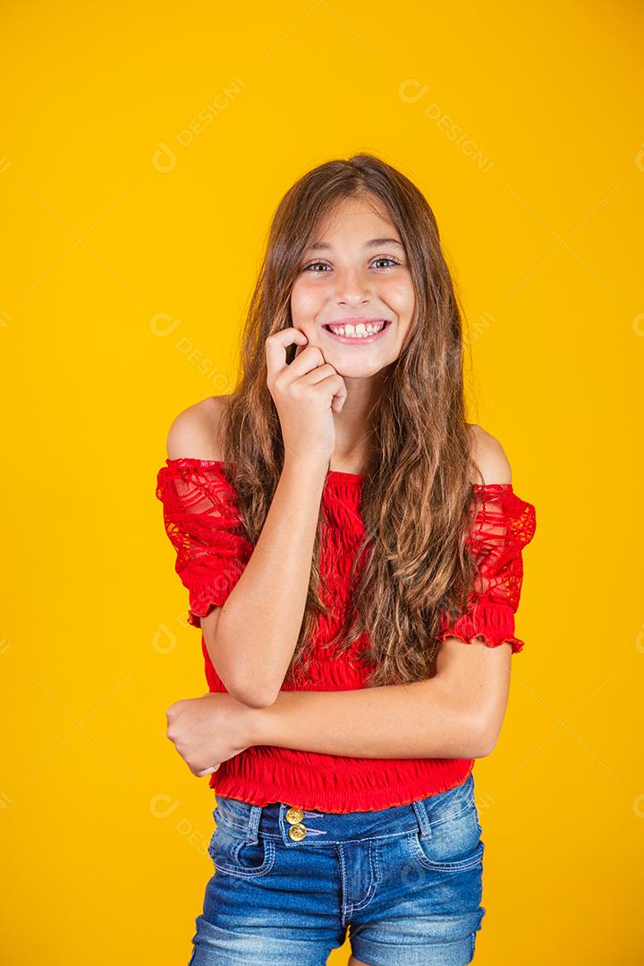 Criança menina feliz em fundo amarelo sorrindo olhando para a câmera.
