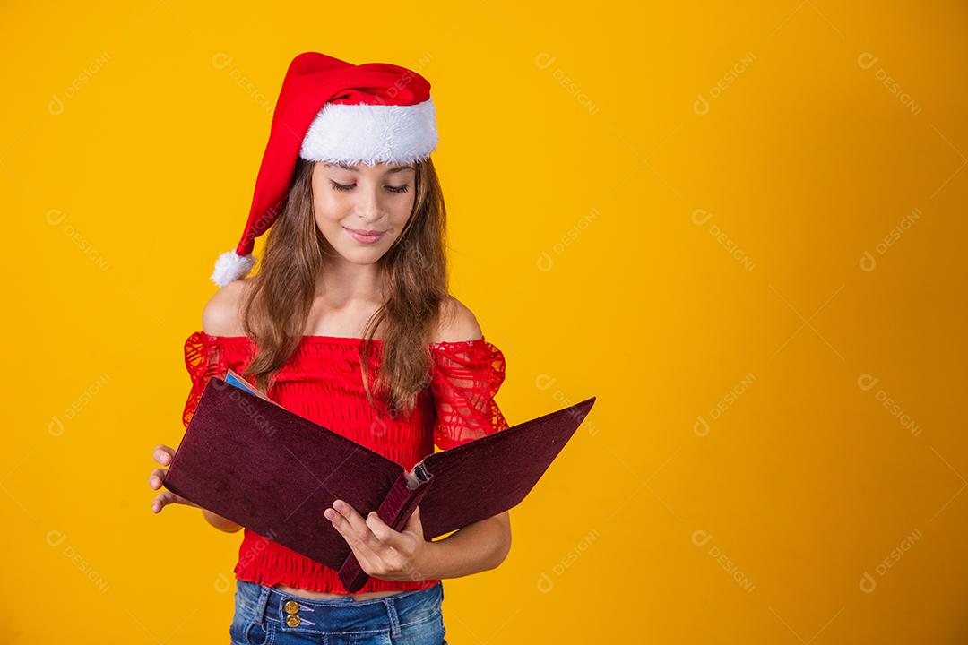 Menina linda criança caucasiana com um livro aveludado vermelho lendo histórias de Natal.