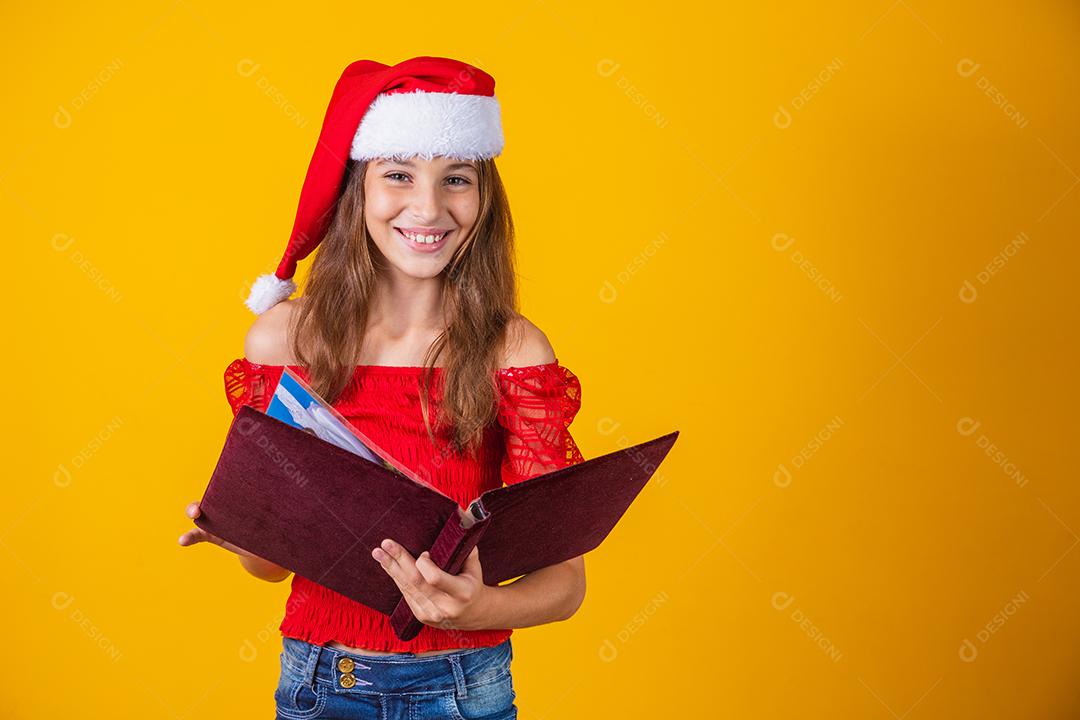 Menina linda criança caucasiana com um livro aveludado vermelho lendo histórias de Natal.
