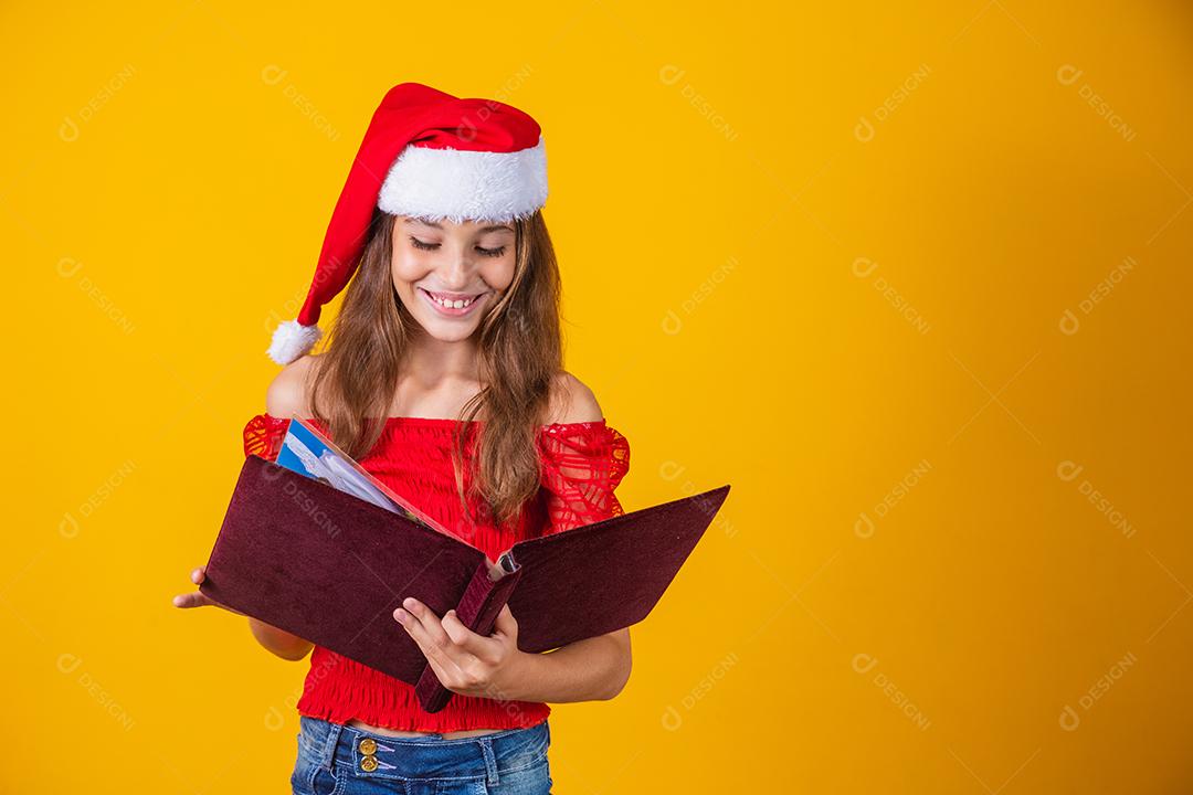 Menina linda criança caucasiana com um livro aveludado vermelho lendo histórias de Natal.