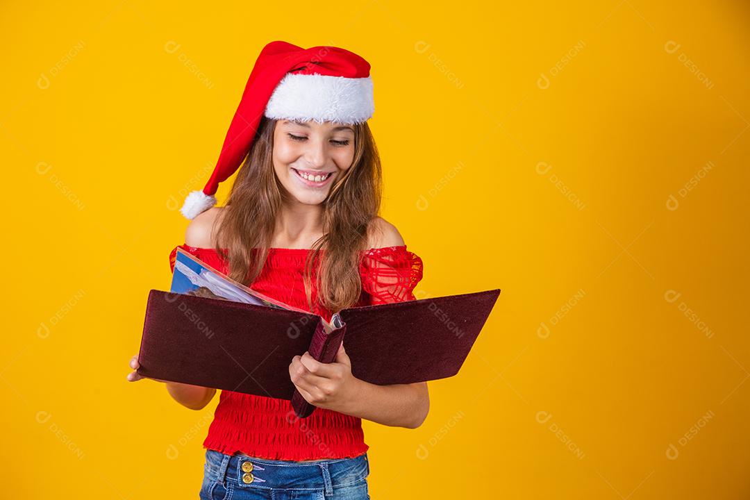 Menina linda criança caucasiana com um livro aveludado vermelho lendo histórias de Natal.