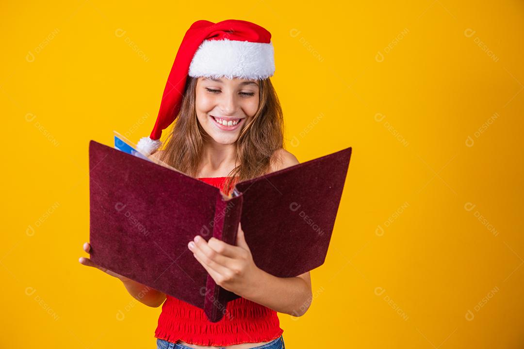Menina linda criança caucasiana com um livro aveludado vermelho lendo histórias de Natal.