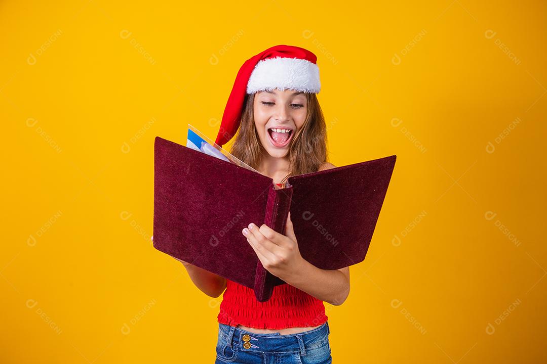 Menina linda criança caucasiana com um livro aveludado vermelho lendo histórias de Natal.