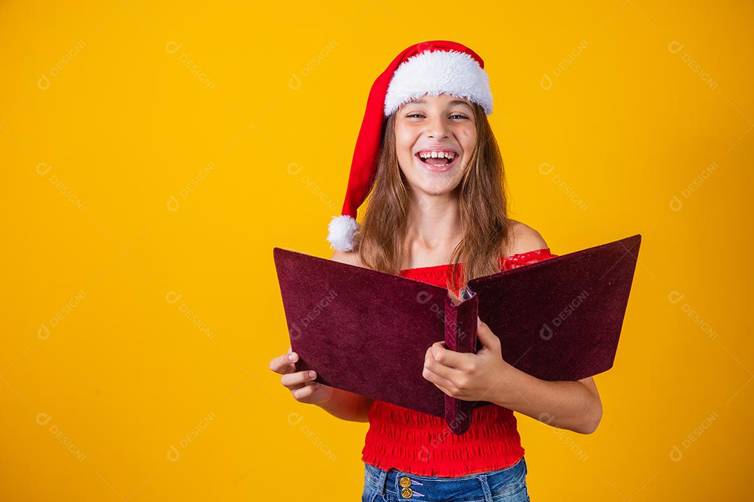 Menina linda criança caucasiana com um livro aveludado vermelho lendo histórias de Natal.