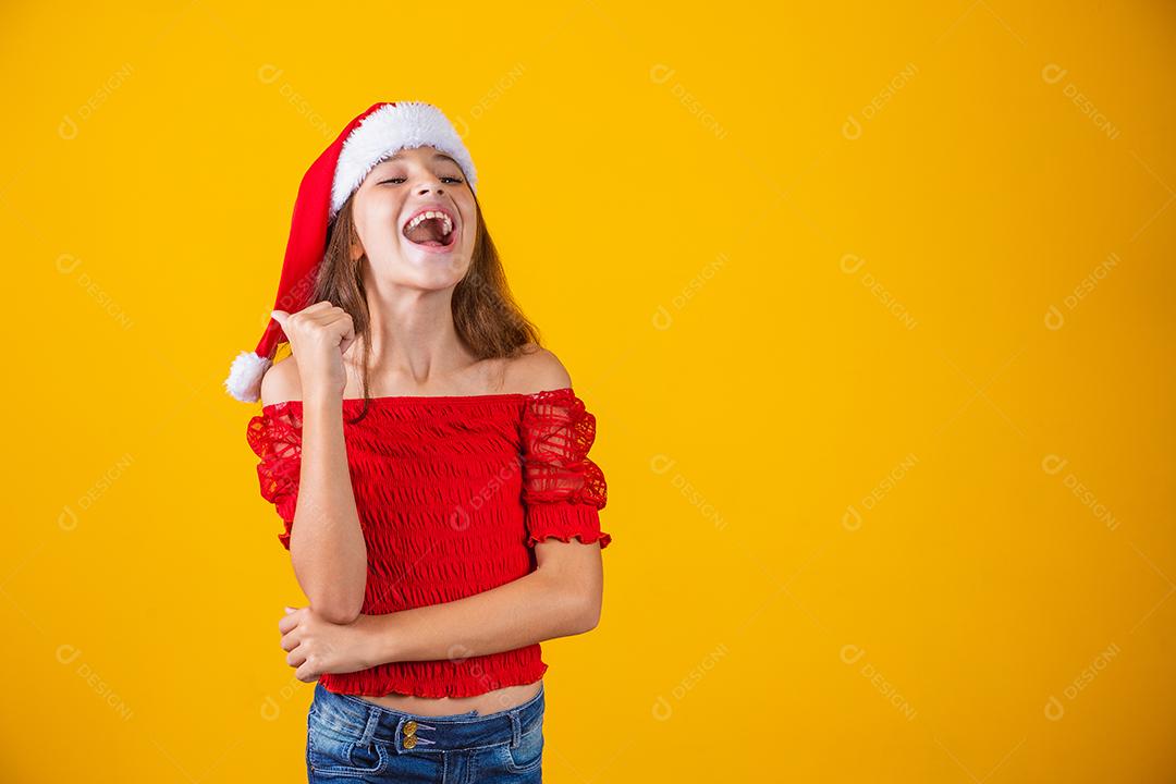 menina vestida para o natal apontando com o polegar no espaço livre para texto. Promoção e campanhas de fim de ano