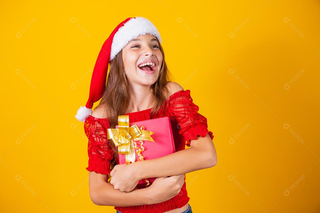 Animado menina caucasiana com a boca aberta, segurando um presente de Natal.