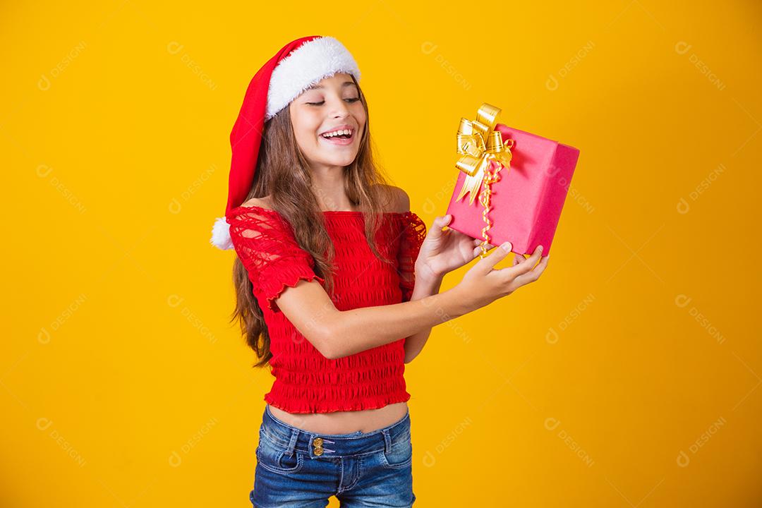 Animado menina caucasiana com a boca aberta, segurando um presente de Natal.