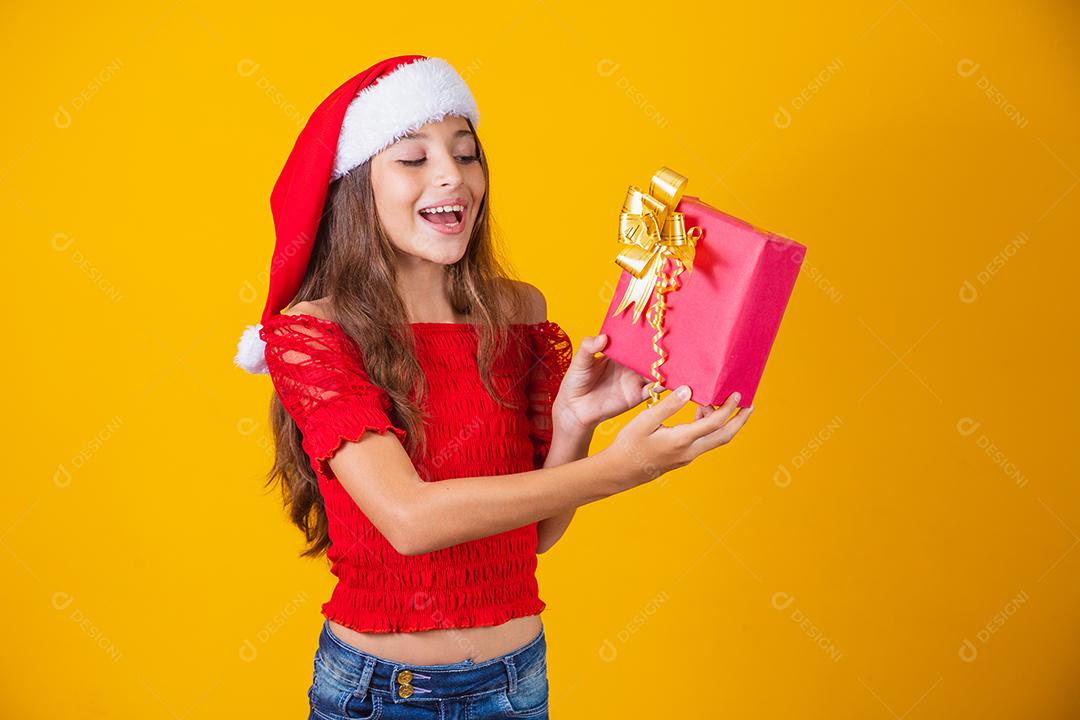 Animado menina caucasiana com a boca aberta, segurando um presente de Natal.