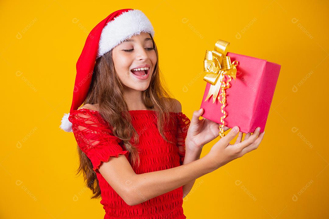 Animado menina caucasiana com a boca aberta, segurando um presente de Natal.