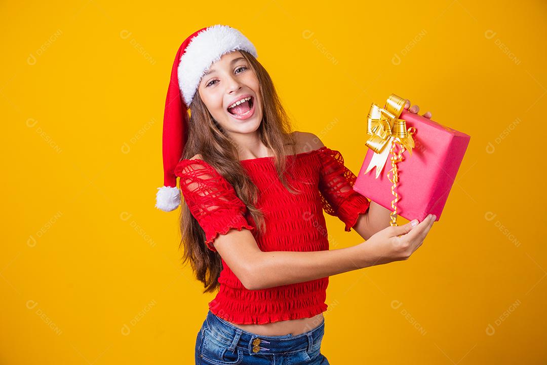 Animado menina caucasiana com a boca aberta, segurando um presente de Natal.