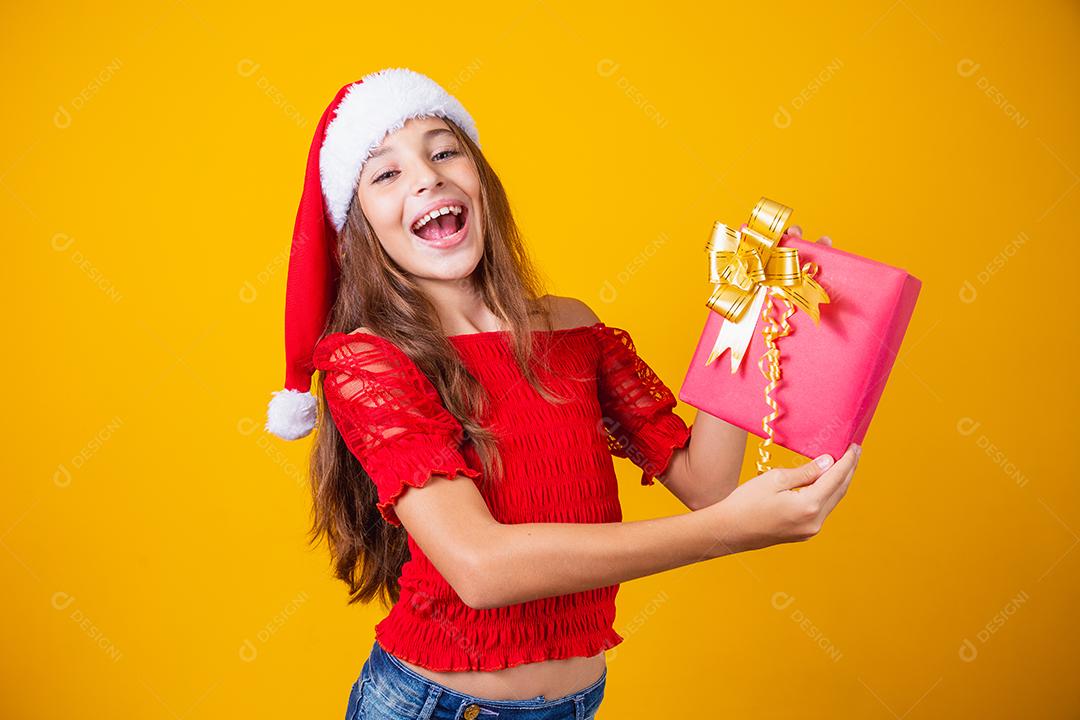 Animado menina caucasiana com a boca aberta, segurando um presente de Natal.