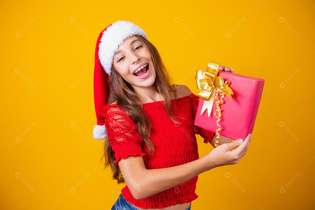 Animado menina caucasiana com a boca aberta, segurando um presente de Natal.