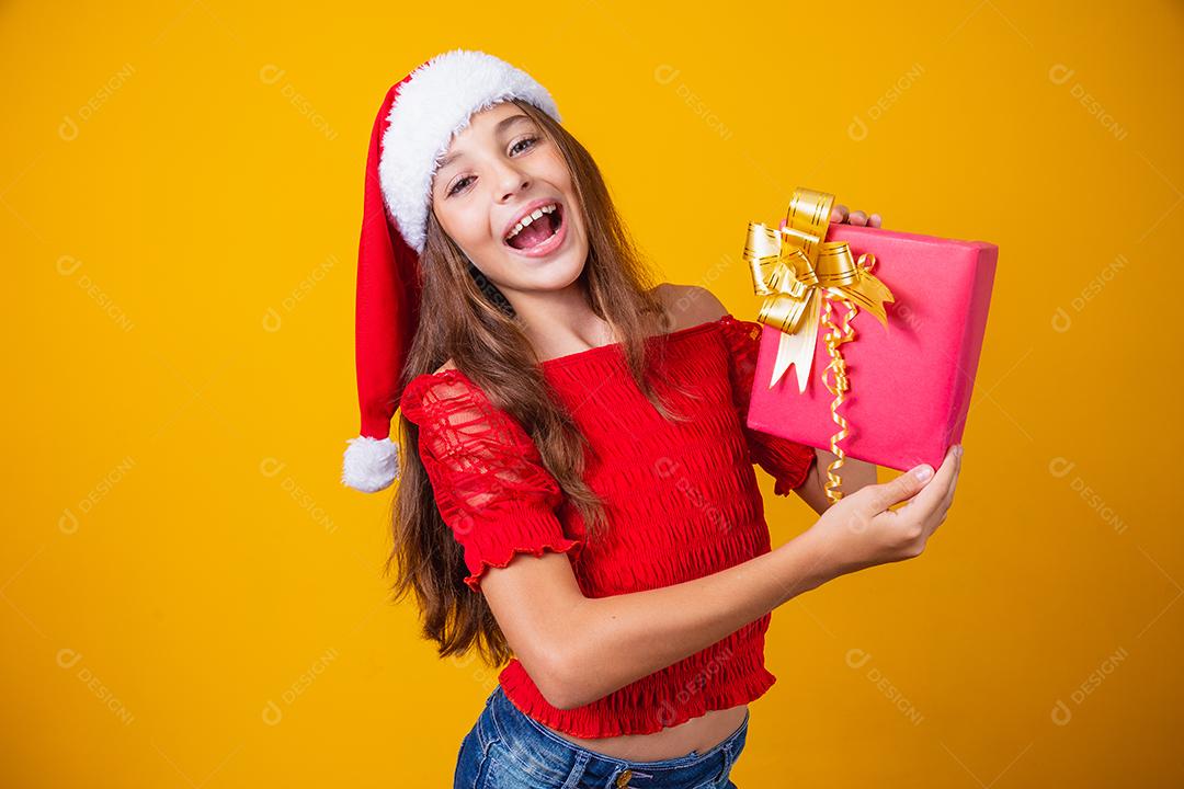 Animado menina caucasiana com a boca aberta, segurando um presente de Natal.