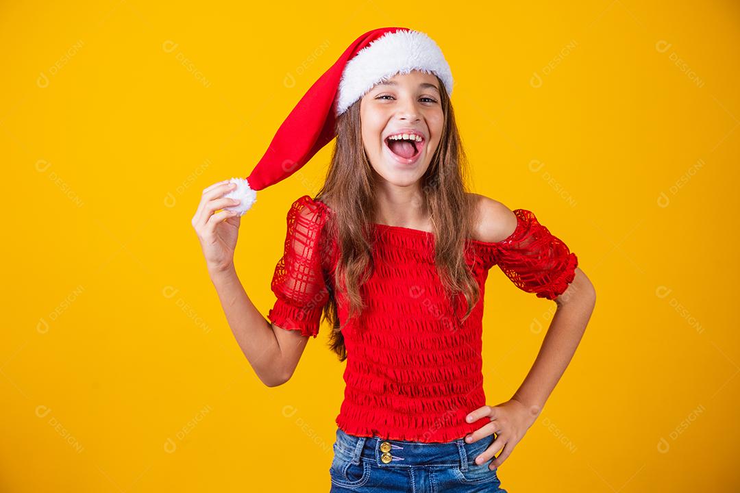 menina vestida para o natal encantada segurando o pompom do chapéu
