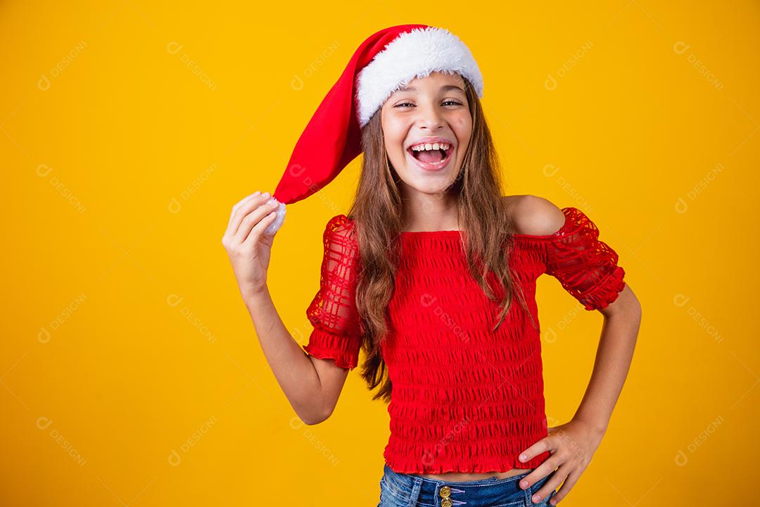 menina vestida para o natal encantada segurando o pompom do chapéu