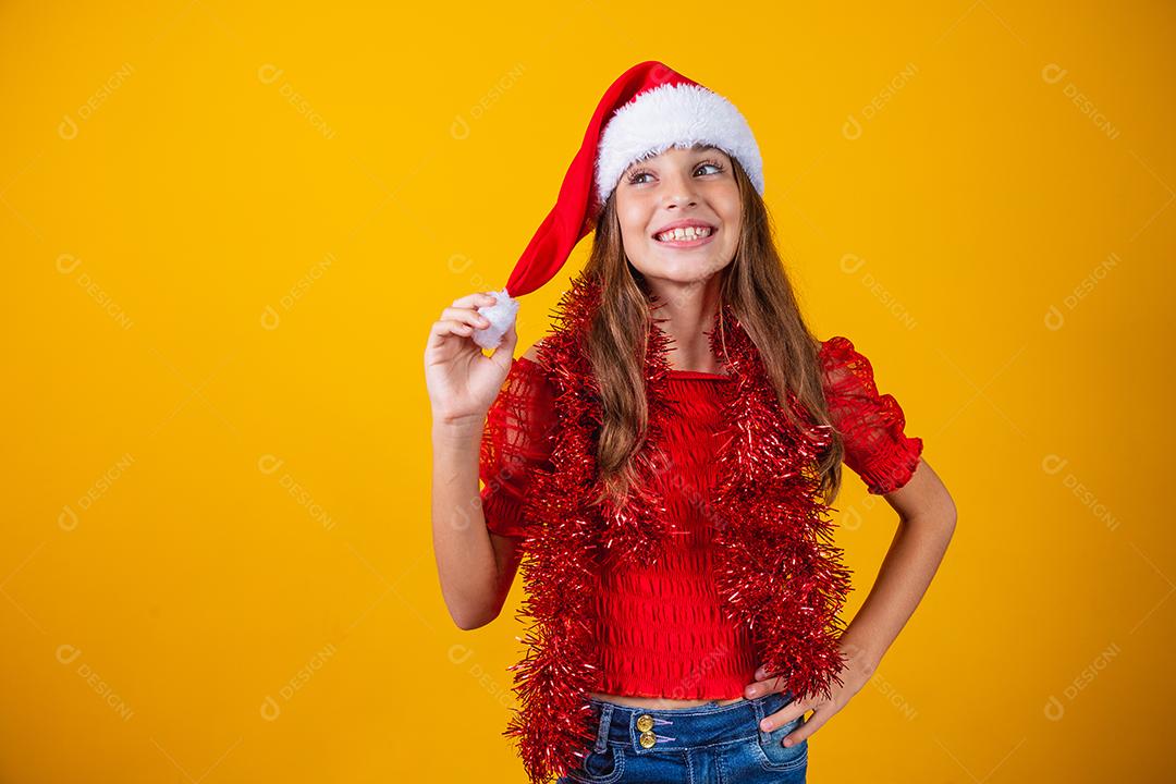 menina vestida para o natal encantada segurando o pompom do chapéu