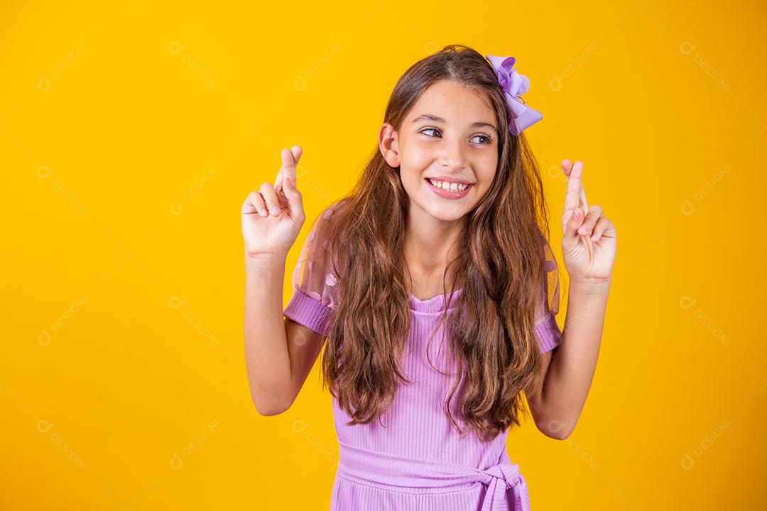 Sonhos e esperanças de infância. Retrato de uma menina adorável em pé com os olhos fechados e cruzando