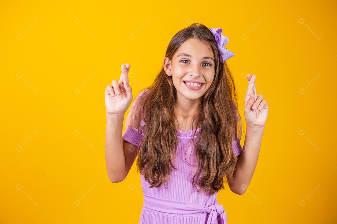 Sonhos e esperanças de infância. Retrato de uma menina adorável em pé com os olhos fechados e cruzando