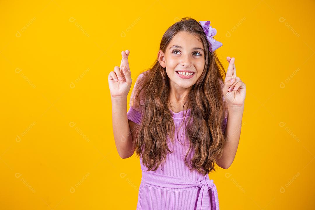 Sonhos e esperanças de infância. Retrato de uma menina adorável em pé com os olhos fechados e cruzando