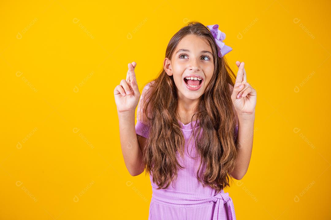 Sonhos e esperanças de infância. Retrato de uma menina adorável em pé com os olhos fechados e cruzando