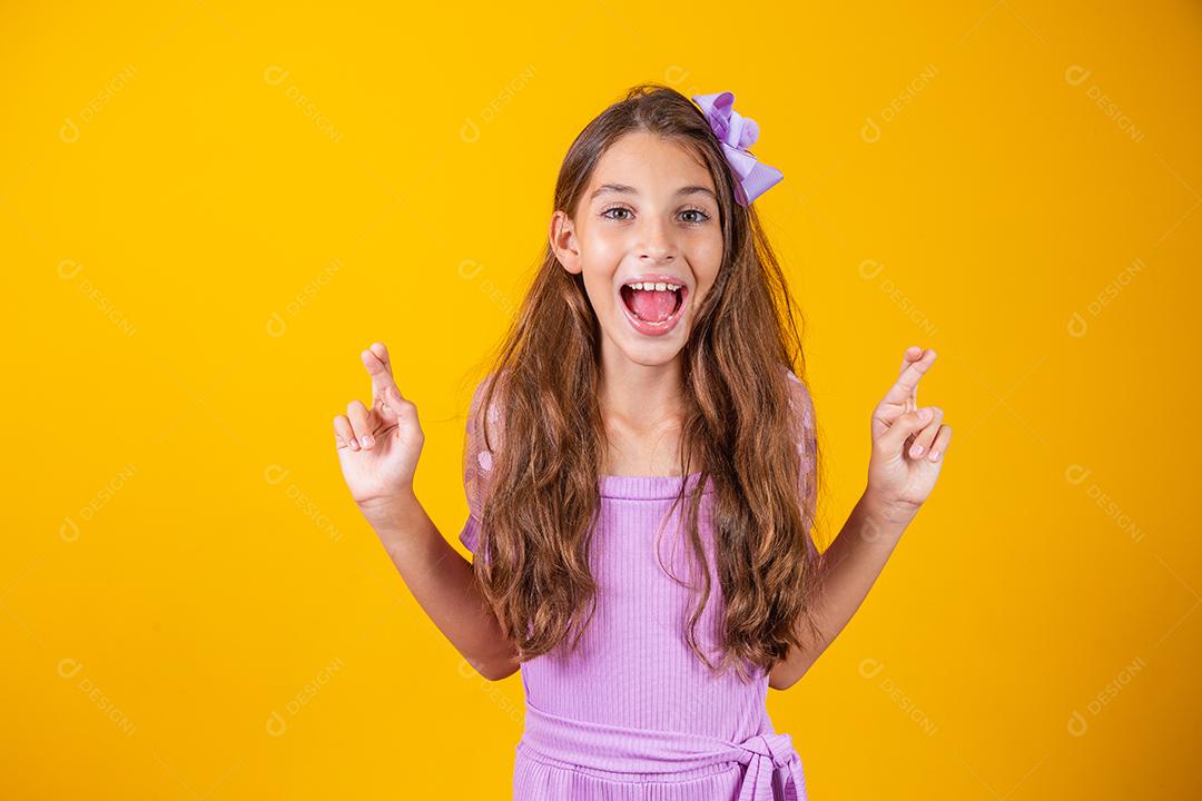 Sonhos e esperanças de infância. Retrato de uma menina adorável em pé com os olhos fechados e cruzando