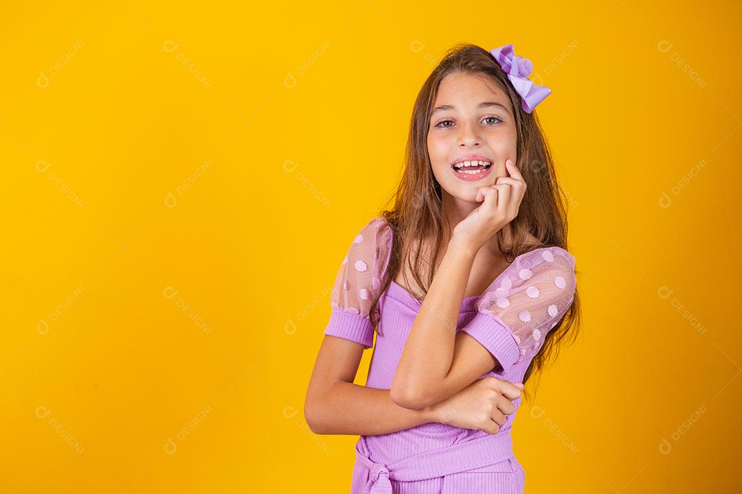 Retrato de uma menina criança sorridente feliz em fundo amarelo.