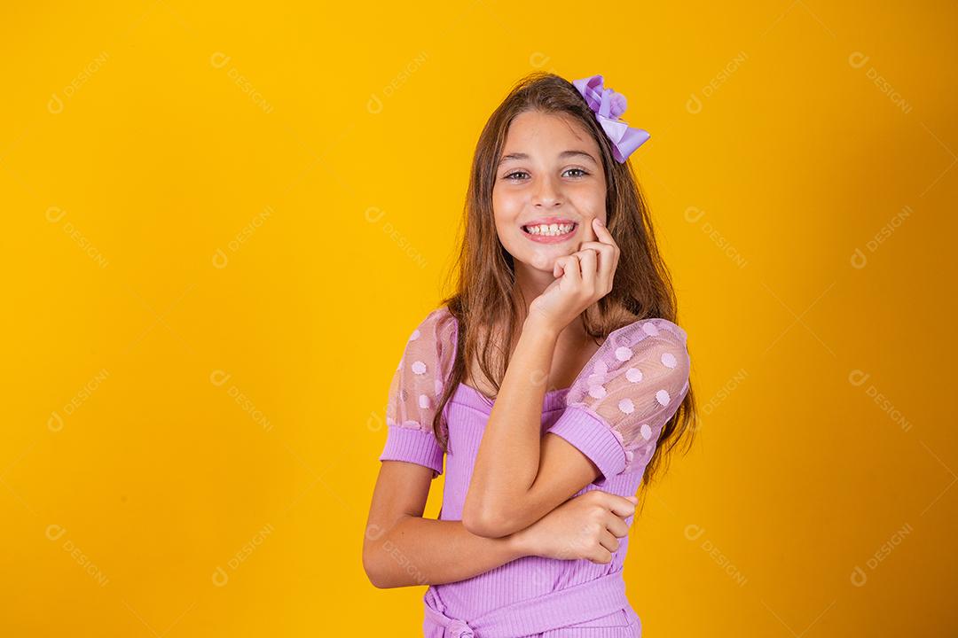 Retrato de uma menina criança sorridente feliz em fundo amarelo.