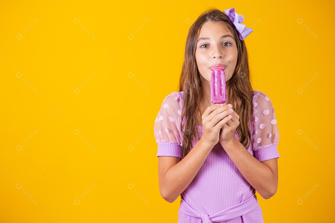 menina comendo um picolé congelado. Adorável menina com delicioso sorvete contra fundo de cor