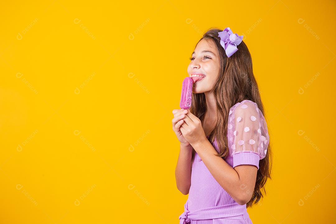Menina comendo um picolé colorido congelado no verão. Garota segurando um picolé