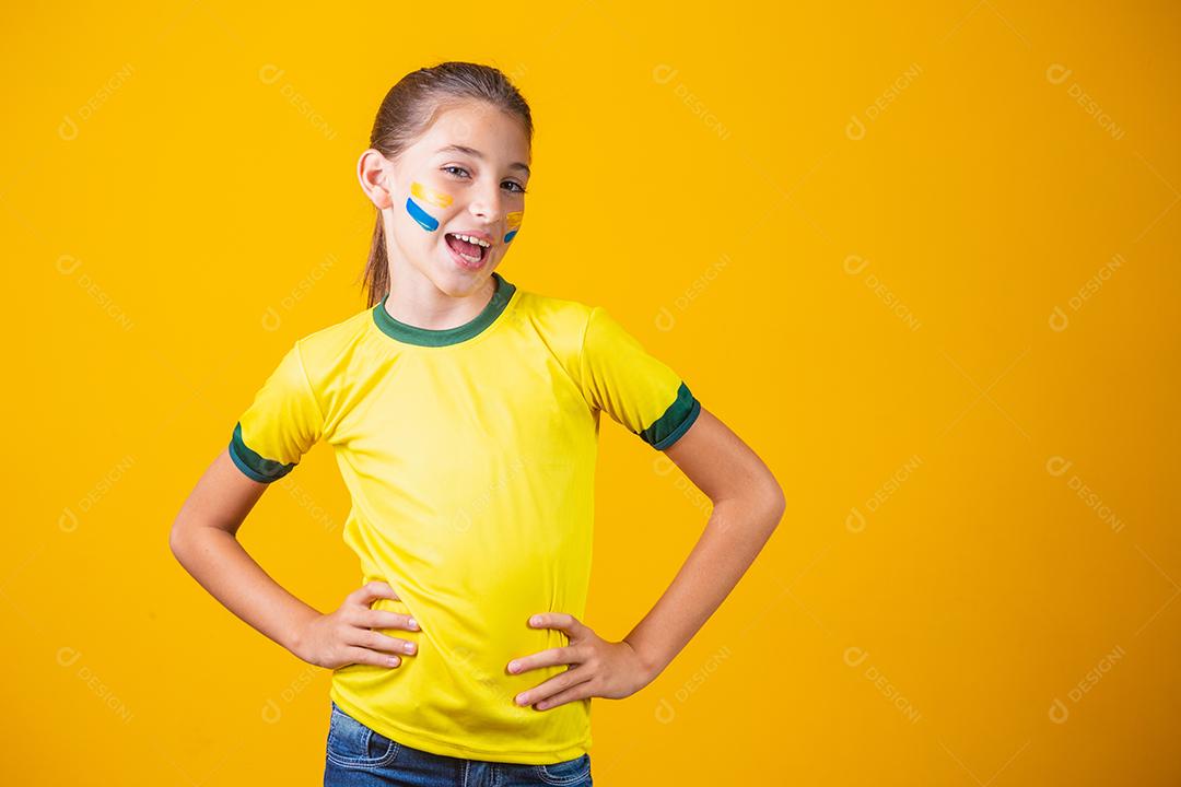 Torcedor de futebol, seleção brasileira. Linda garotinha torcendo por seu time em fundo amarelo
