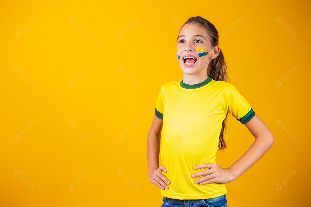 Torcedor de futebol, seleção brasileira. Linda garotinha torcendo por seu time em fundo amarelo