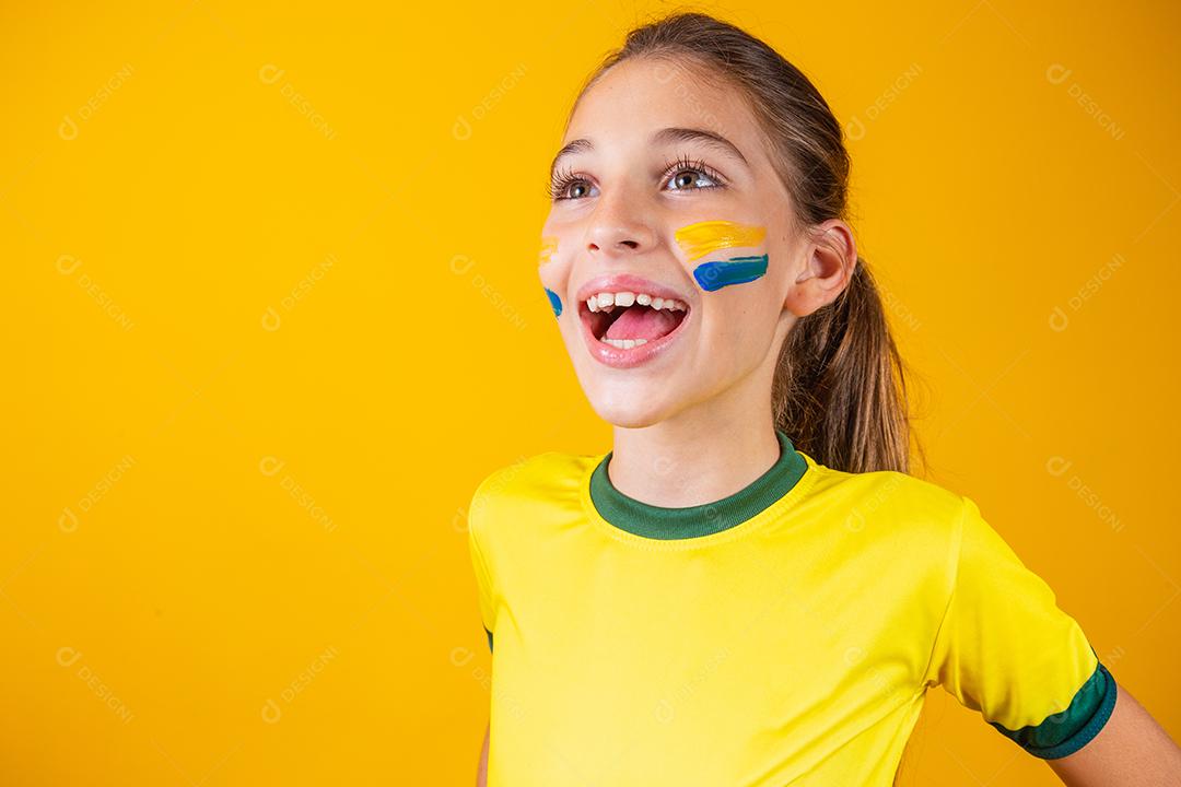 Torcedor de futebol, seleção brasileira. Linda garotinha torcendo por seu time em fundo amarelo