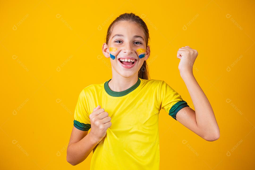 Torcedor de futebol, seleção brasileira. Linda garotinha torcendo por seu time em fundo amarelo