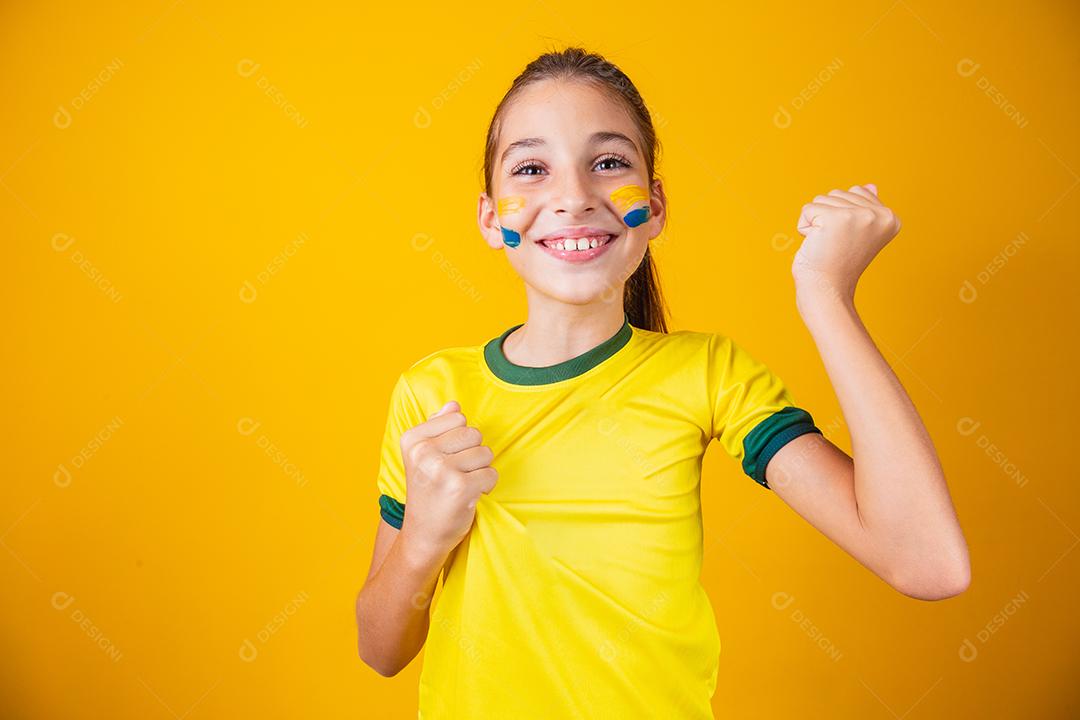 Torcedor de futebol, seleção brasileira. Linda garotinha torcendo por seu time em fundo amarelo