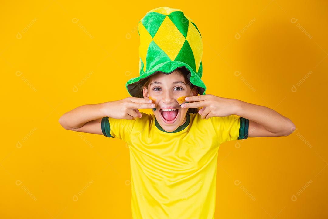 Linda garotinha torcendo por seu time em fundo amarelo com rosto pintado. fã brasileira