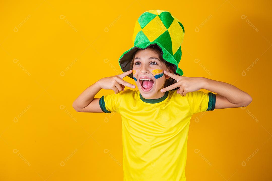 Linda garotinha torcendo por seu time em fundo amarelo com rosto pintado. fã brasileira