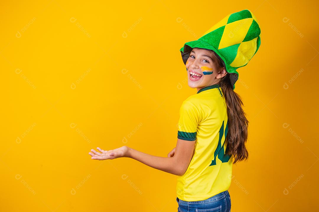 menina fã brasileira com as costas no fundo amarelo com camisa do brasil