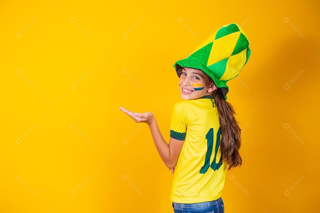 menina fã brasileira com as costas no fundo amarelo com camisa do brasil
