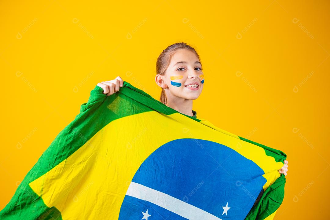 pequena garota caucasiana com bandeira do brasil em fundo amarelo. apoiador de criança brasileira