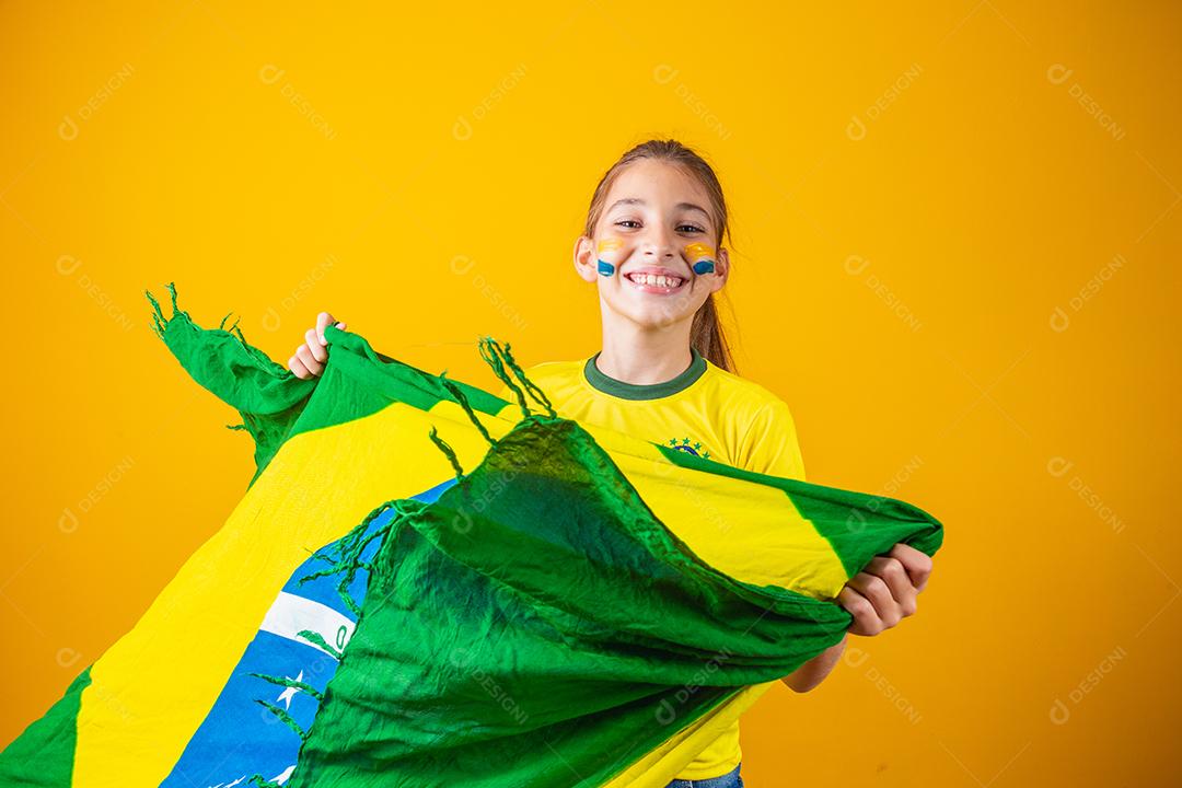 pequena garota caucasiana com bandeira do brasil em fundo amarelo. apoiador de criança brasileira