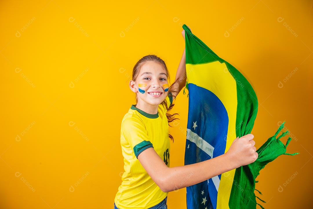pequena garota caucasiana com bandeira do brasil em fundo amarelo. apoiador de criança brasileira